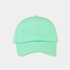 Close-up of distressed mint green baseball cap with vintage washed fabric and ripped details