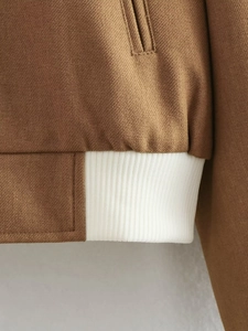 Detailed close-up of brown twill fabric with white ribbed hem stitching on biker jacket