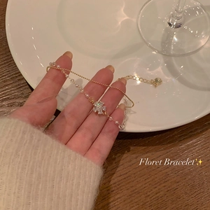 Detalle de pulsera de perlas doradas con colgante de flor de circón en fondo elegante