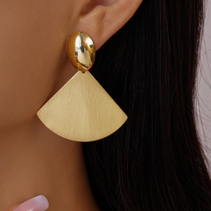 Detail of gold fan-shaped geometric earrings with brushed metal texture and sleek finish