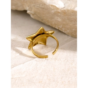 Detailed macro view of a gold-plated star-shaped adjustable open ring on a stone base