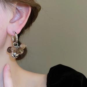 Macro view of silver hoop earrings featuring gradient brown resin beads and silver accent