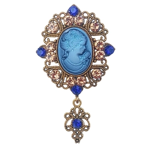 Dettaglio macro di spilla cammeo vintage con cristalli blu e filigrana floreale bronzo