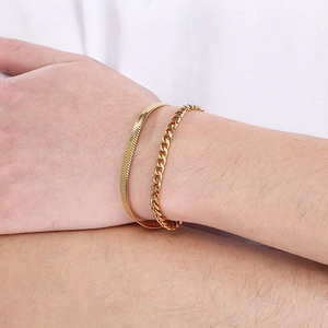 Close-up of double-layer gold snake and cuban link chain bracelets worn on a wrist