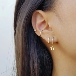 Detail of gold S925 silver hoop earrings set with zircon studs and star charm on ear