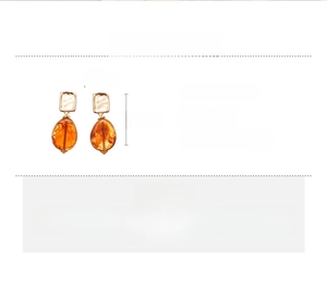 Close-up of vintage square metal earrings with amber acrylic teardrop pendants