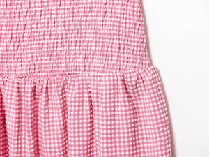 Détail d'une robe midi vichy rose avec smocks élastiques et texture seersucker