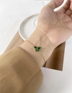Close-up of gold butterfly bracelet featuring four green marquise-cut zircon stones