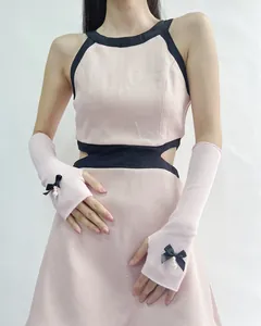 Detail of pink knitted arm sleeves with black ribbon bows and pearl accents