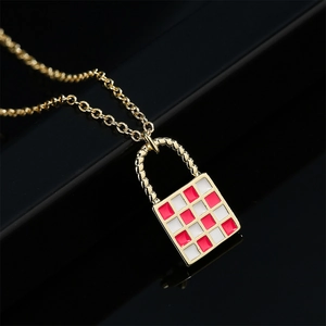 Gold lock necklace with red and white checkered pattern on a dark background