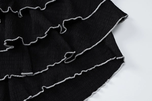 Détail macro du tissu plissé noir avec bordure à volants blanche pour ensemble d'été