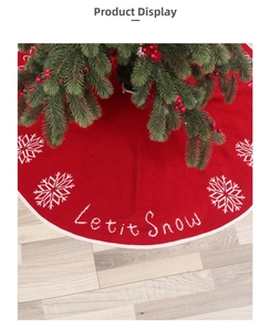 Detail of red knit Christmas tree skirt with white Let it Snow embroidery and snowflakes
