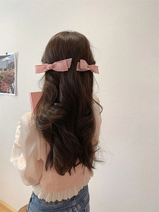 Rosa Schleifen-Haarspangen in langem gewelltem Haar zeigen die Rückansicht des Stylings