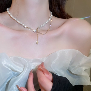 Detail of French style pearl necklace with heart pendant on model neckline