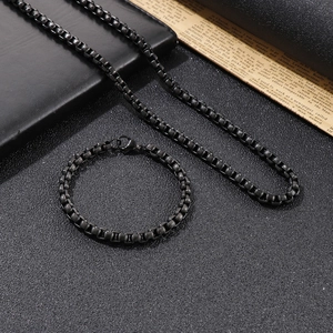 Detail of hiphop black titanium steel box chain necklace and bracelet set on vintage book