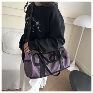 Detail view of purple gym bag with mesh stitching and black straps held by a model