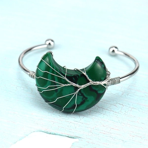 Macro detail of silver wire wrapped malachite moon on a handmade tree of life cuff bracelet