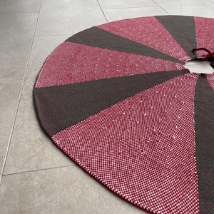 Detailed knit texture of red and green scalloped Christmas tree skirt with white dots