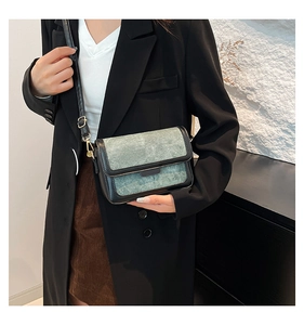 Detail of adjustable leather strap and denim texture on a vintage crossbody bag