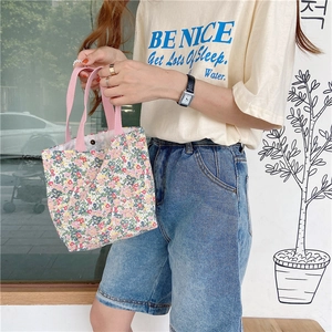 Detailed outdoor shot of a small floral canvas tote bag with pink webbing handles