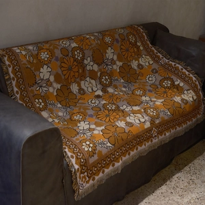 Macro view showing the thick woven texture and colorful floral patterns of the sofa throw