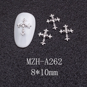 Macro detail of silver cross nail charm with zircon inlay on textured black surface