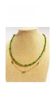 Detail of layered gold necklace with faceted green beads and colored accents on a bust stand