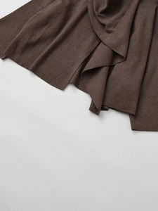 Detail of soft dark brown knitted fabric showing fine texture and elegant draping effect