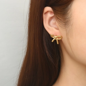 Fashionable bow-shaped 18K gold-plated stainless steel stud earring on female model