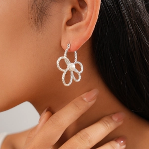 Nahaufnahme der silbernen Hohlblüten-Ohrringe mit Perle am Ohr eines Models