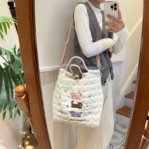 Close-up of heart-quilted cream tote bag featuring colorful pet embroidery and soft texture
