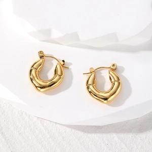 Detail view of gold-plated geometric U-shaped hoop earrings with polished bamboo texture