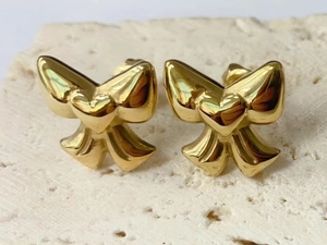 Macro shot of 14K gold-plated bow earrings with heart center on stone background