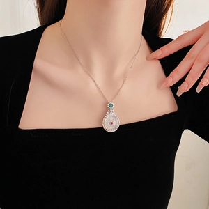 Detail view of a silver gemstone necklace with white inlay and red center on a neck