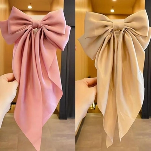 Detailed view of layered satin bow hair clips in soft pink and champagne beige colors