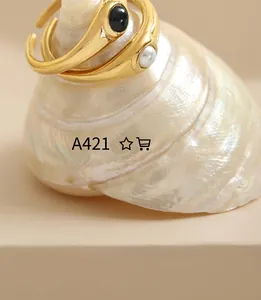 Close-up of gold irregular rings set with black stone and pearl on a shell display
