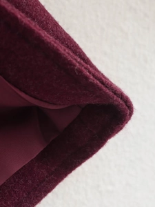 Close-up of wine red wool jacket showcasing high-quality stitching and smooth inner lining