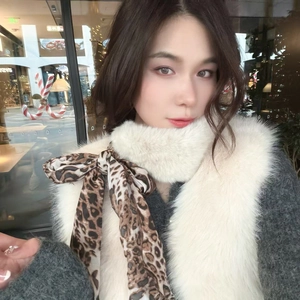 Detail of soft faux fur winter scarf with leopard print ribbon bow and plush texture