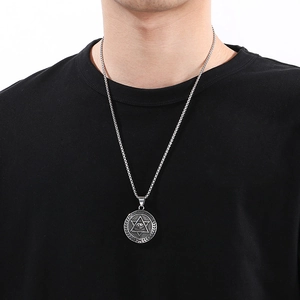 Silver stainless steel Eye of Providence pendant necklace on a male model's black T-shirt