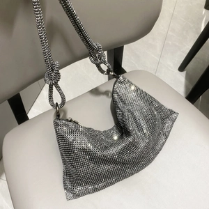 Detail shot of a silver rhinestone hobo bag with knotted shoulder strap on a chair