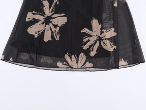 Close-up of double-layer mesh fabric with elegant beige floral print on a black dress