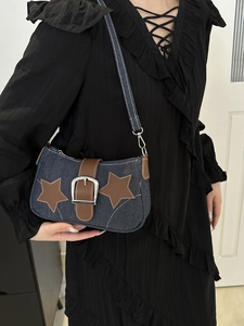 Detail of blue denim hobo bag featuring brown faux leather star and silver buckle strap