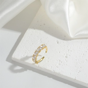 Adjustable gold open ring featuring a clear rectangular zircon on white silk background