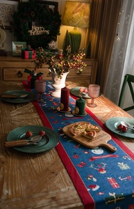 Blue Christmas table runner with Santa and reindeer patterns on a festive wooden dinner table