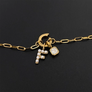 Elegante collana in acciaio al titanio dorato con lettera F in perle e ciondolo di cristallo