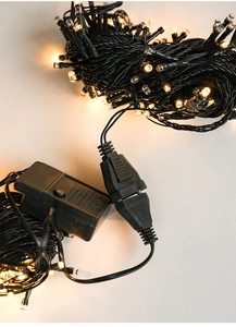 Close-up of warm white LED string light controller and plug with dark green wire