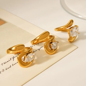 Detail of three gold rings with marquise, pear and emerald cut zircons on a white surface