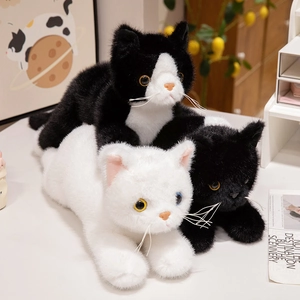 Lifelike plush cat stuffed animals in orange, white, and black on a cozy home desk