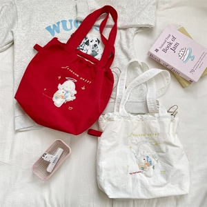 Detail of red and beige canvas drawstring tote bags with cute cartoon lamb embroidery