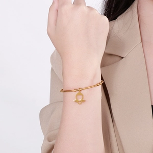 Detail of gold thin bangle with open heart pendant on female wrist close-up view